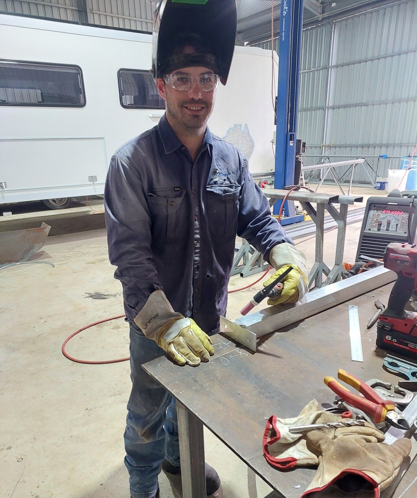 Brad at a work bench holding a welding gun