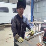 Brad at a work bench holding a welding gun