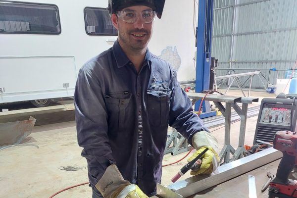 Brad at a work bench holding a welding gun